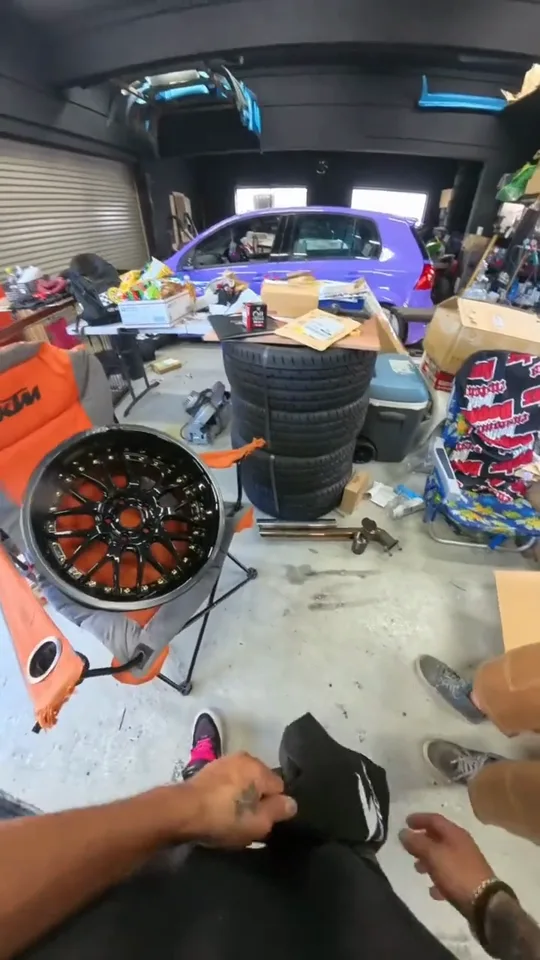 ホイールと工具が並ぶ工場の中を、作業するスタッフの目線で撮った動画のカット